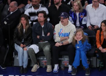 Actors Jason Bateman and Jason Sudeikis sitting courtside with their families at an NBA game.