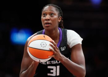 Tina Charles holding a basketball, looking up.
