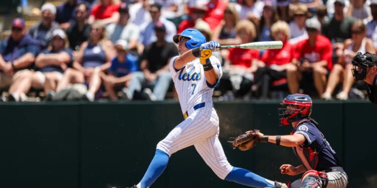 Roman Martin of UCLA batting a baseball with a catcher behind him.