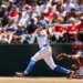 Roman Martin of UCLA batting a baseball with a catcher behind him.