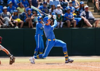 A baseball player in a blue and yellow uniform swinging a bat during a game.