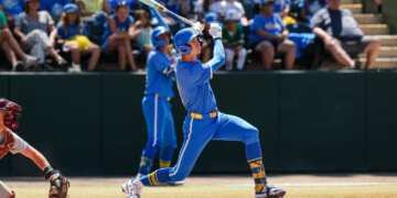 A baseball player in a blue and yellow uniform swinging a bat during a game.