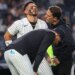 New York Yankees shortstop José Caballero reacts in pain after being hit by a pitch, as manager Aaron Boone and a trainer check on him.
