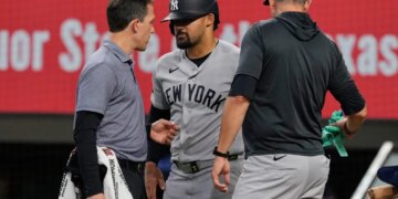 New York Yankees' Jasson Dominguez, center, talks with a team trainer as manager Aaron Boone, right, looks on after Dominguez was hit by a pitch in the fourth inning of a baseball game against the Texas Rangers Wednesday, April 29, 2026, in Arlington, Texas.