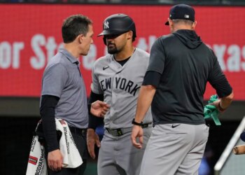 Jasson Dominguez, center, speaks with a team trainer while manager Aaron Boone looks on.