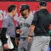 Jasson Dominguez, center, speaks with a team trainer while manager Aaron Boone looks on.