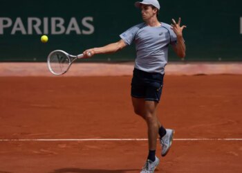 Zachary Svajda hitting a forehand return during a tennis match at the French Open.