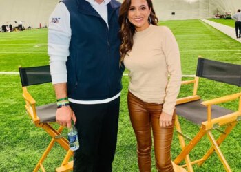 Mike Vrabel and reporter Dianna Russini standing together on an indoor football field.