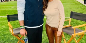Mike Vrabel and reporter Dianna Russini standing together on an indoor football field.