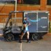 An Amazon Prime delivery driver looks at their phone next to an Amazon Mubea U-Mobility E-Cargobike.