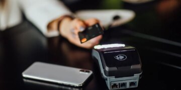 Person paying with a credit card at a restaurant using a credit card reader.