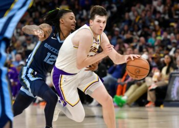 Austin Reaves of the Lakers handling the ball against Ja Morant of the Grizzlies.