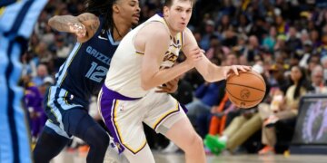 Austin Reaves of the Lakers handling the ball against Ja Morant of the Grizzlies.