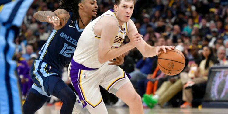 Austin Reaves of the Lakers handling the ball against Ja Morant of the Grizzlies.