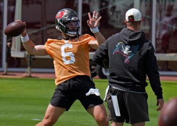 Baker Mayfield in an orange jersey throwing a football.