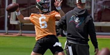 Baker Mayfield in an orange jersey throwing a football.