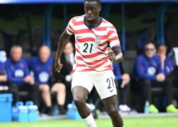 United States forward Tim Weah (21) on the field with a soccer ball.
