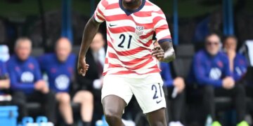 United States forward Tim Weah (21) on the field with a soccer ball.