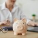 A piggy bank on a desk, with a financial advisor calculating a budget in the background.