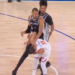 A San Antonio Spurs player falling over an opposing player on the basketball court.