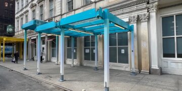 Models of proposed sidewalk sheds in teal and yellow on a city street.