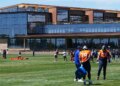 Denver Broncos players practicing football drills in front of the team's new headquarters.