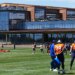Denver Broncos players practicing football drills in front of the team's new headquarters.