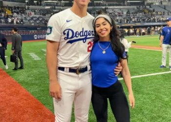 Bobby Miller, wearing a Dodgers uniform, and Natalie Loureda, in a blue shirt, smiling on a baseball field.