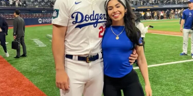 Bobby Miller, wearing a Dodgers uniform, and Natalie Loureda, in a blue shirt, smiling on a baseball field.