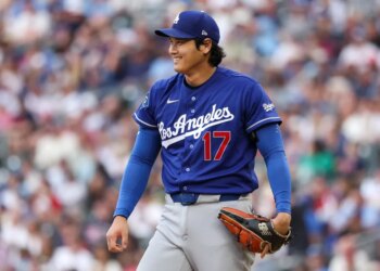 Dodgers starting pitcher Shohei Ohtani smiles after a play during a game.