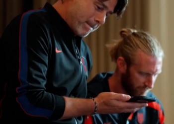 Two men in athletic wear looking at a phone.