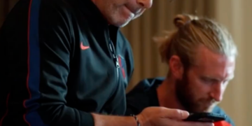 Two men in athletic wear looking at a phone.