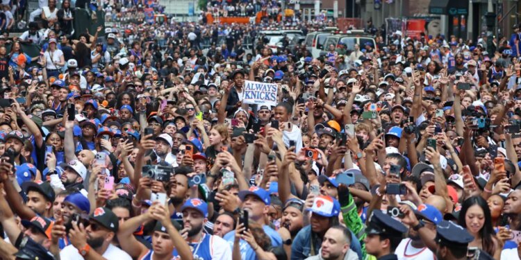 Crowds of fans wearing New York Knicks gear celebrate at a ticker-tape parade in Lower Manhattan.