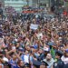 Crowds of fans wearing New York Knicks gear celebrate at a ticker-tape parade in Lower Manhattan.