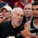 San Antonio Spurs coach Gregg Popovich talking with Victor Wembanyama on the bench.