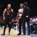 Knicks guard Jalen Brunson observes as Atlanta Hawks head coach Quin Snyder disputes a call with a referee.