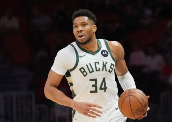 Giannis Antetokounmpo dribbles the ball in a white Milwaukee Bucks jersey.