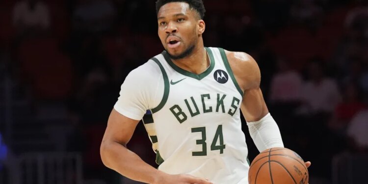 Giannis Antetokounmpo dribbles the ball in a white Milwaukee Bucks jersey.