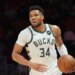 Giannis Antetokounmpo dribbles the ball in a white Milwaukee Bucks jersey.