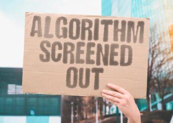 A hand holding up a cardboard sign that says "ALGORITHM SCREENED OUT" in capital letters.
