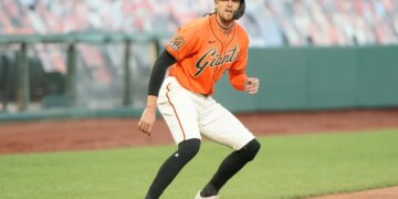 A San Francisco Giants baseball player on a base, wearing an orange jersey with "Giants" written across the chest and a black batting helmet.