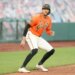 A San Francisco Giants baseball player on a base, wearing an orange jersey with "Giants" written across the chest and a black batting helmet.