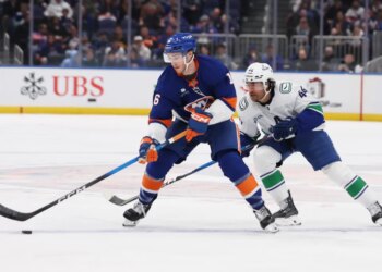 New York Islanders center Marc Gatcomb and Vancouver Canucks left wing Kiefer Sherwood chase the puck.