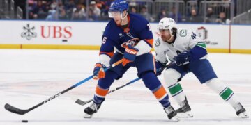 New York Islanders center Marc Gatcomb and Vancouver Canucks left wing Kiefer Sherwood chase the puck.