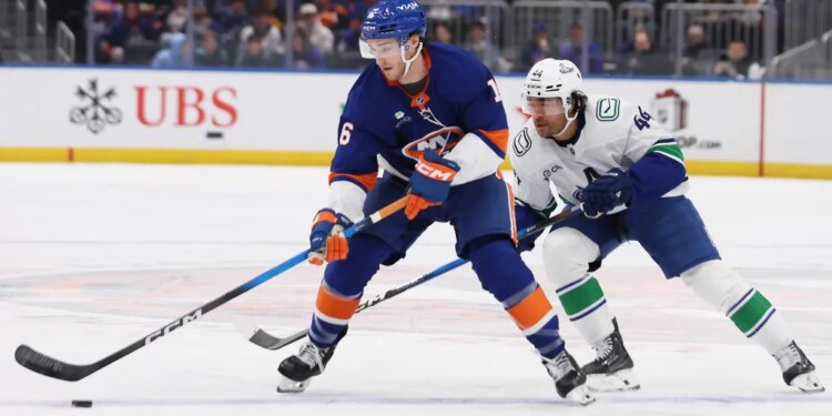 New York Islanders center Marc Gatcomb and Vancouver Canucks left wing Kiefer Sherwood chase the puck.
