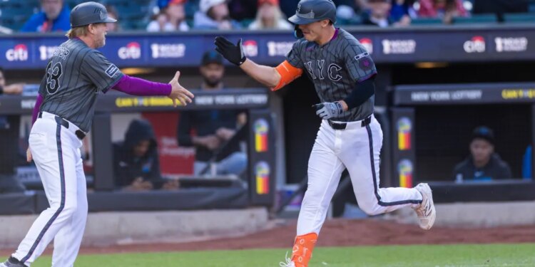 New York Mets first baseman Jared Young is high-fiving a coach after scoring a solo home run.