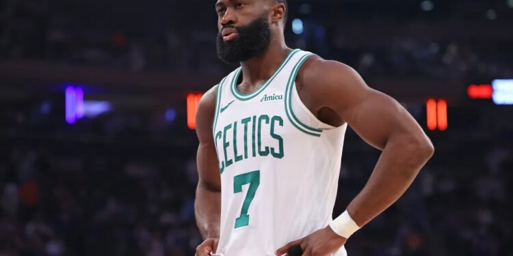 Jaylen Brown of the Boston Celtics wearing a white jersey with green trim and the number 7, hands on hips, looking intently to the left.