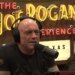Joe Rogan wearing headphones and speaking into a microphone.