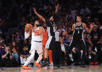 New York Knicks player Karl-Anthony Towns (#32) drives with the ball against San Antonio Spurs guard Stephon Castle (#5) and guard #1 in Game 3 of the 2026 NBA Finals.