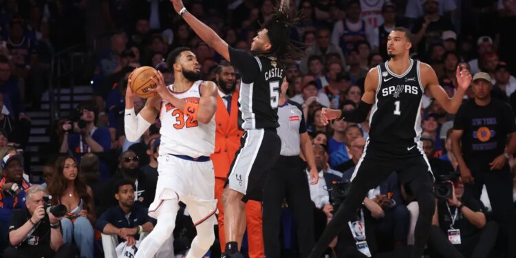 New York Knicks player Karl-Anthony Towns (#32) drives with the ball against San Antonio Spurs guard Stephon Castle (#5) and guard #1 in Game 3 of the 2026 NBA Finals.